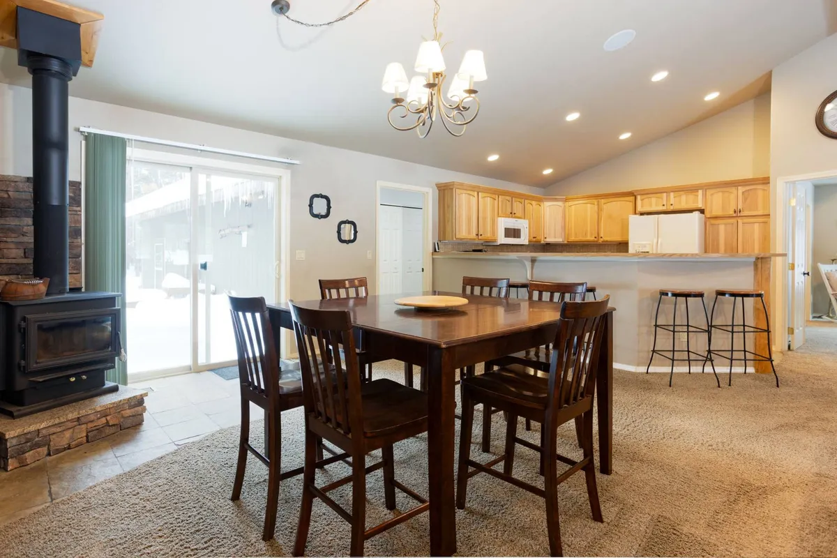 A dining area featuring a wooden table and chairs, a chandelier overhead, and a stove nearby, creating a welcoming space for shared meals and gatherings after outdoor activities.